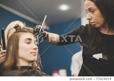 Eyebrow dyeing. The master paints eyebrows with henna to a beautiful girl, paints with a brush in the salon of a beautician-makeup artist. Brow architecture Eyebrow dyeing. The master paints eyebrows with henna to a beautiful girl, paints with a brush in the salon of a beautician-makeup artist. Brow architecture 73924034