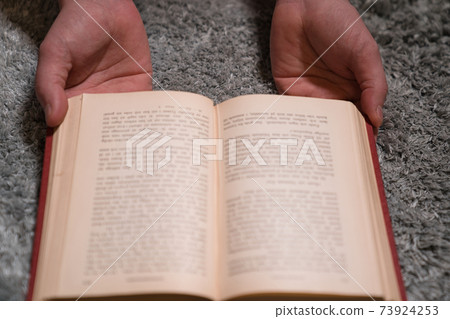手拿著一本打開的書在地毯上 手拿著一本打開的書在地毯上 73924253