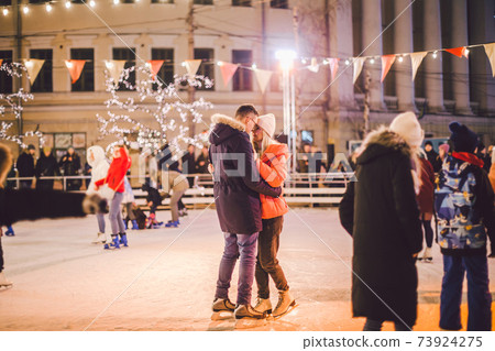 Beautiful couple have fun in ice arena. active date ice skating on ice arena in evening city square in winter Christmas Eve. St. Valentine's Day at the city ice rink. New Year's holidays in city Kiev Beautiful couple have fun in ice arena. active date ice skating on ice arena in evening city square in winter Christmas Eve. St. Valentine's Day at the city ice rink. New Year's holidays in city Kiev 73924275