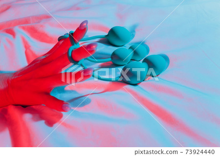 Woman holding anal balls in bed close-up. Woman holding anal balls in bed close-up. 73924440