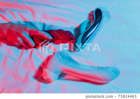 Woman in bedroom holding vibrator in hand. Woman in bedroom holding vibrator in hand. 73924463