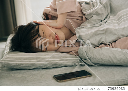 Image of a woman who has trouble getting up and a Japanese woman who wakes up with an alarm on her smartphone Image of a woman who has trouble getting up and a Japanese woman who wakes up with an alarm on her smartphone 73926083