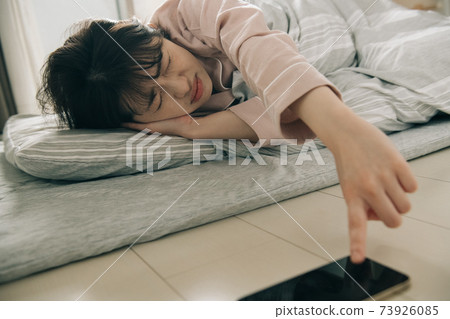 Image of a woman who has trouble getting up and a Japanese woman who wakes up with an alarm on her smartphone Image of a woman who has trouble getting up and a Japanese woman who wakes up with an alarm on her smartphone 73926085