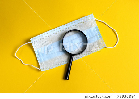 magnifying glass on protective mask. concept of timely diagnosis and search for diseases 73930884