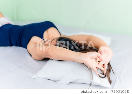 Young attractive asian woman stretching hands while lying in bed in the morning. Focus on the hand. Young attractive asian woman stretching hands while lying in bed in the morning. Focus on the hand. 73931038