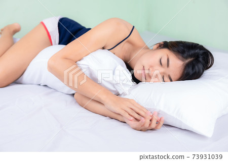 Asian woman lying and sleep on the bed hugging bolster Asian woman lying and sleep on the bed hugging bolster 73931039