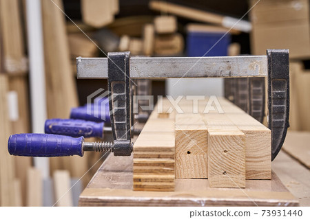 Joinery. Gluing and clamping wooden detail. Production of wood furniture. Furniture manufacture. Close-up Joinery. Gluing and clamping wooden detail. Production of wood furniture. Furniture manufacture. Close-up 73931440