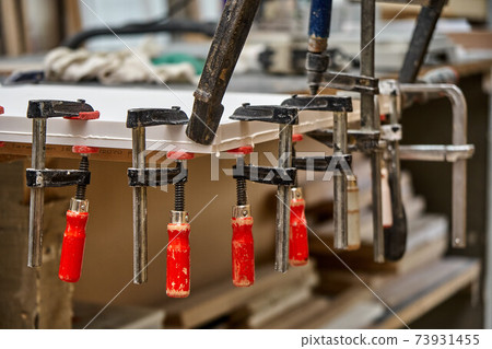Joinery. Gluing and clamping table top of acrylic stone. Production of wood furniture. Furniture manufacture. Close-up 73931455