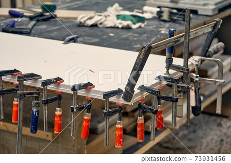Joinery. Gluing and clamping table top of acrylic stone. Production of wood furniture. Furniture manufacture. Close-up 73931456