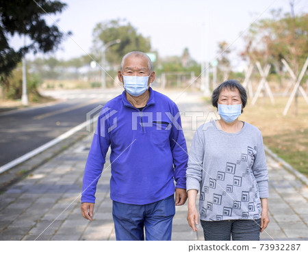 Asian senior couple wearing face mask and walking on street Asian senior couple wearing face mask and walking on street 73932287