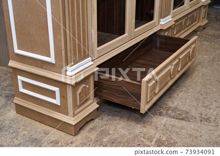 Joinery. Mdf cabinet carcass with moldings and carved base. Wooden furniture manufacturing process Joinery. Mdf cabinet carcass with moldings and carved base. Wooden furniture manufacturing process 73934091