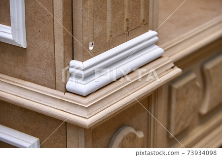 Joinery. Mdf cabinet carcass with moldings and carved base. Wooden furniture manufacturing process Joinery. Mdf cabinet carcass with moldings and carved base. Wooden furniture manufacturing process 73934098