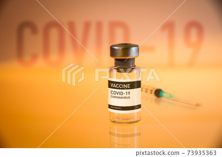 Covid-19 vaccine bottle and syringe on a yellow background Covid-19 vaccine bottle and syringe on a yellow background 73935363