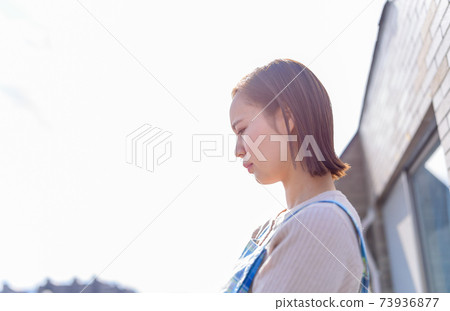 A housewife standing on the balcony with a dull look A housewife standing on the balcony with a dull look 73936877