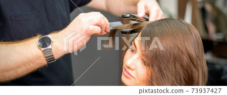 Hairdresser is straightening the hair Hairdresser is straightening the hair 73937427