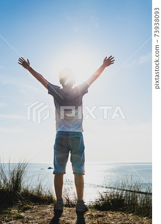 Netherlands, weastkapelle. North sea landscape. A Caucasian boy is inspired by nature and raises his arms to the sky. Netherlands, weastkapelle. North sea landscape. A Caucasian boy is inspired by nature and raises his arms to the sky. 73938093
