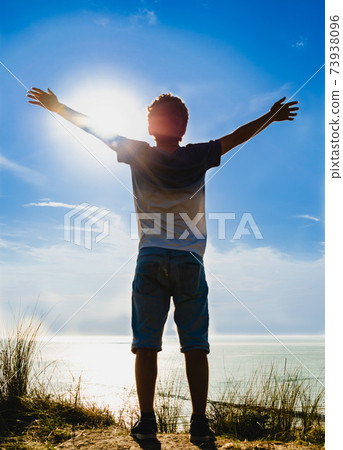 Netherlands, weastkapelle. North sea landscape. A Caucasian boy is inspired by nature and raises his arms to the sky. Netherlands, weastkapelle. North sea landscape. A Caucasian boy is inspired by nature and raises his arms to the sky. 73938096