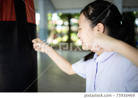 Asian student girl is crying and raising fists,female people is punching into punch bag takes out her anger,emotional explosion,stress relief,feels angry,disappointed,self- loathing,catharsis concept 73938469
