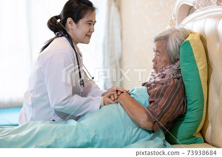 Elderly mother with depressive symptoms or Alzheimer woman feel sad asian female doctor or daughter holding elderly patient hand comforting support in bedroom at home health care depression concept 73938684