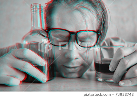 A drunk man in glasses sleeps on a table with a bottle and a glass and the effect of the glitch of a black white photograph. A drunk man in glasses sleeps on a table with a bottle and a glass and the effect of the glitch of a black white photograph. 73938748