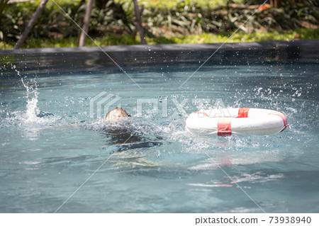 Asian child girl struggling for a life buoy in swimming pool to rescue drowning in dangerous situation in summer vacation, lifebuoy or ringbuoy equipment for save life in water, concept of safety 73938940