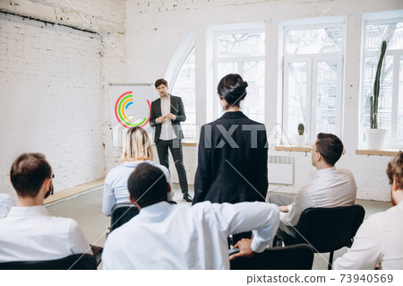 Male speaker giving presentation in hall at workshop. Audience or conference hall. Rear view of unrecognized participants. Male speaker giving presentation in hall at workshop. Audience or conference hall. Rear view of unrecognized participants. 73940569