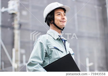 一個穿著工作服的人站在一個建築工地 73943558