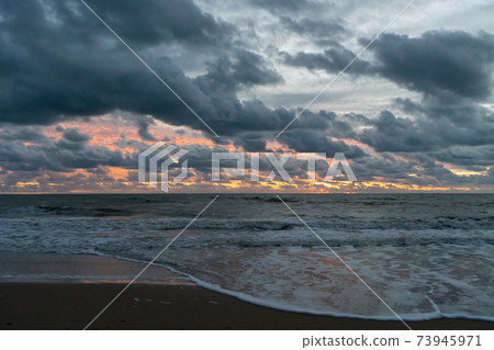 Coastline with sandy beach, heavy clouds and incoming waves during sunset Coastline with sandy beach, heavy clouds and incoming waves during sunset 73945971