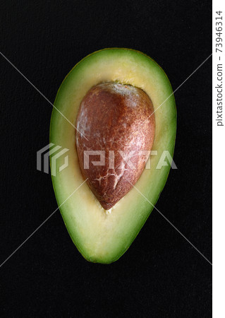 Macro shot of fresh avocados cut in a half on the black background 73946314