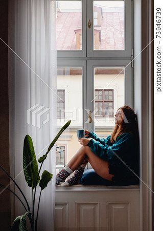 Woman sitting on the big windowsill 73946739