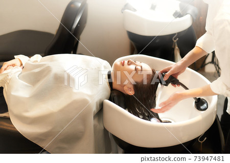 Young woman having her hair washed at a beauty salon Young woman having her hair washed at a beauty salon 73947481