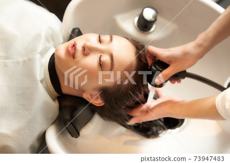 Young woman having her hair washed at a beauty salon Young woman having her hair washed at a beauty salon 73947483
