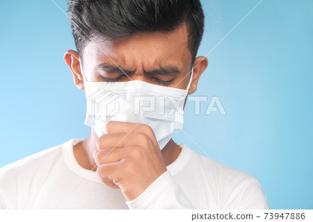 young man in surgical mask coughing and sneezes close up  73947886