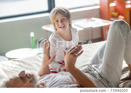 Happy child sitting on bed near dad 73948205