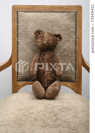 shabby teddy bear sitting in an old vintage armchair 73949452