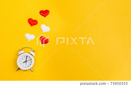 Alarm clock and hearts on yellow background. Place for text. Top view. Time for love 73950355