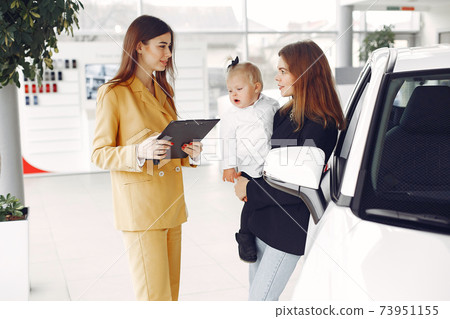 Elegant woman with little daughter in a car salon Elegant woman with little daughter in a car salon 73951155