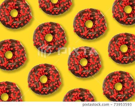 Flat lay donuts in chocolate glaze pattern on a yellow background. Top view 73953593