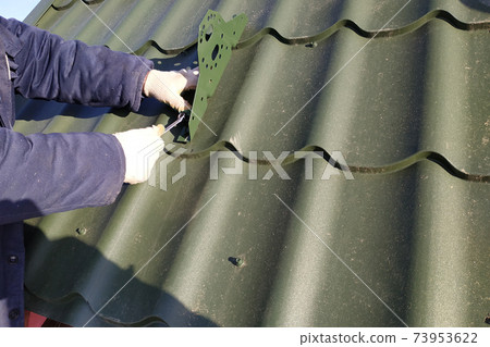 In the cold season, the worker fastens the roof elements to the roof 73953622