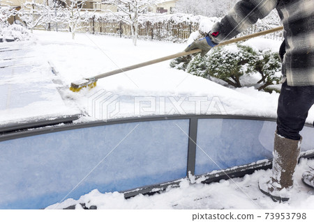 A man cleans snow from a water pool outdoor. A man cleans snow from a water pool outdoor. 73953798