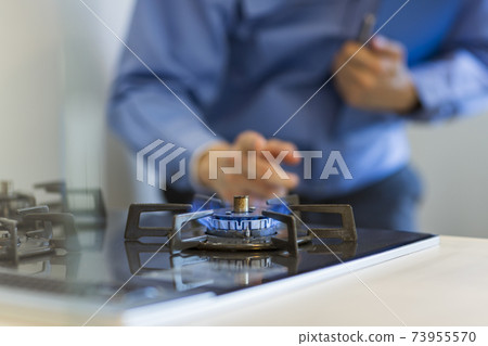 一個穿著工作服的人檢查燃氣灶 73955570