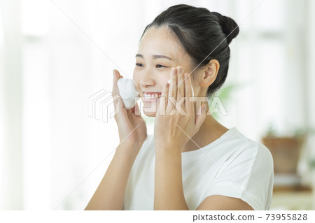 A young woman cleansing face A young woman cleansing face 73955828