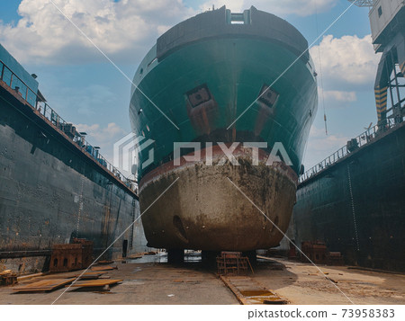 Industry view - Ocean Vessel in the dry dock in shipyard. Old rusty ship under repair 73958383