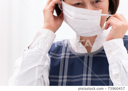 Woman in the middle of wearing a mask Woman in the middle of wearing a mask 73960457