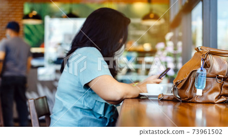 Mini alcohol gel bottle to kill Corona Virus(Covid-19) hang on a brown leather shoulder bag with hot coffee on table in cafe.New normal lifestyle.Health care concept.Selective focus on alcohol gel Mini alcohol gel bottle to kill Corona Virus(Covid-19) hang on a brown leather shoulder bag with hot coffee on table in cafe.New normal lifestyle.Health care concept.Selective focus on alcohol gel 73961502