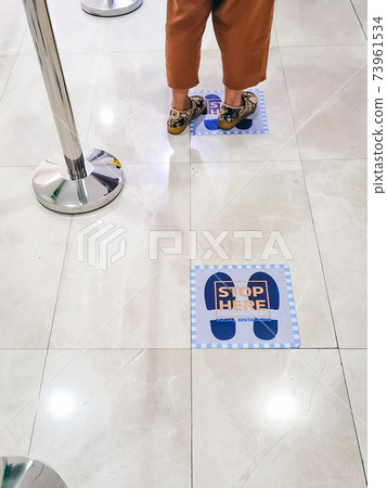 STAND HERE foot sign or symbol on floor in hospital. Hospital set foot sign for social distancing to wait for go up the elevator. New normal lifestyle. Prevention the spread of Corona Virus (COVID-19) 73961534