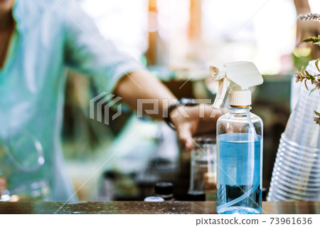 Blue alcohol sprayer bottle for hands cleaning to prevent the spreading of the Corona virus (Covid-19),Place the entrance service for customers in the cafe. Healthcare concept. New normal lifestyle. Blue alcohol sprayer bottle for hands cleaning to prevent the spreading of the Corona virus (Covid-19),Place the entrance service for customers in the cafe. Healthcare concept. New normal lifestyle. 73961636