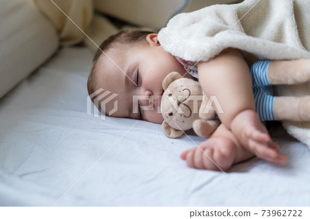 Childhood, care, motherhood, health concepts - Close up Little peace calm infant toddler baby girl sleep resting take deep nap laying hug teddy bear toy on soft warm blanket with close eyes on big bed Childhood, care, motherhood, health concepts - Close up Little peace calm infant toddler baby girl sleep resting take deep nap laying hug teddy bear toy on soft warm blanket with close eyes on big bed 73962722
