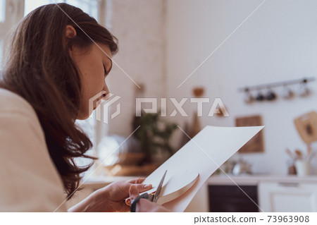 The person cuts the valentine with scissors from the paper. A gift for a sweetheart. Recognition of love The person cuts the valentine with scissors from the paper. A gift for a sweetheart. Recognition of love 73963908