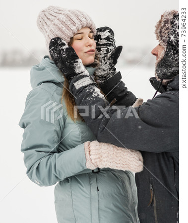 Portrait of smiling couple in love looking at each other. Young happy couple walking in winter Portrait of smiling couple in love looking at each other. Young happy couple walking in winter 73964233